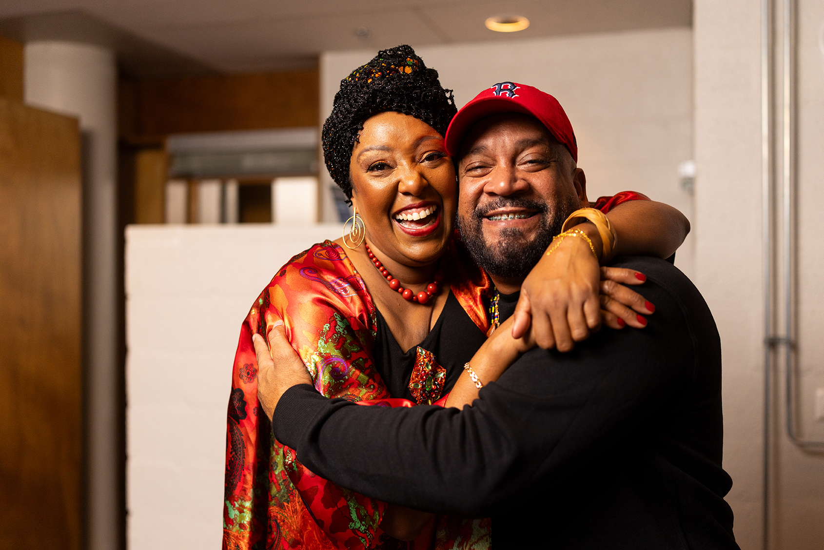 This photo shows two people smiling and hugging each other. On the left you'll see a woman, Betsayda Machado, and on the right a man, DJ Babatr.